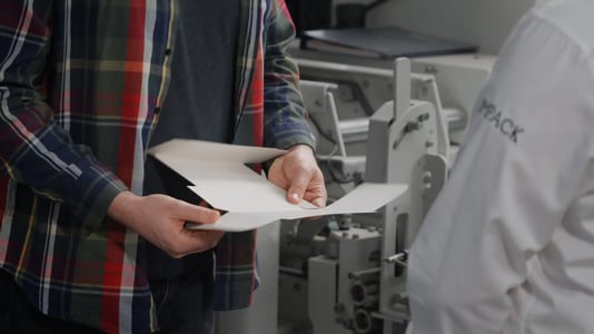 A production manager analyzing a box near a folder-gluer