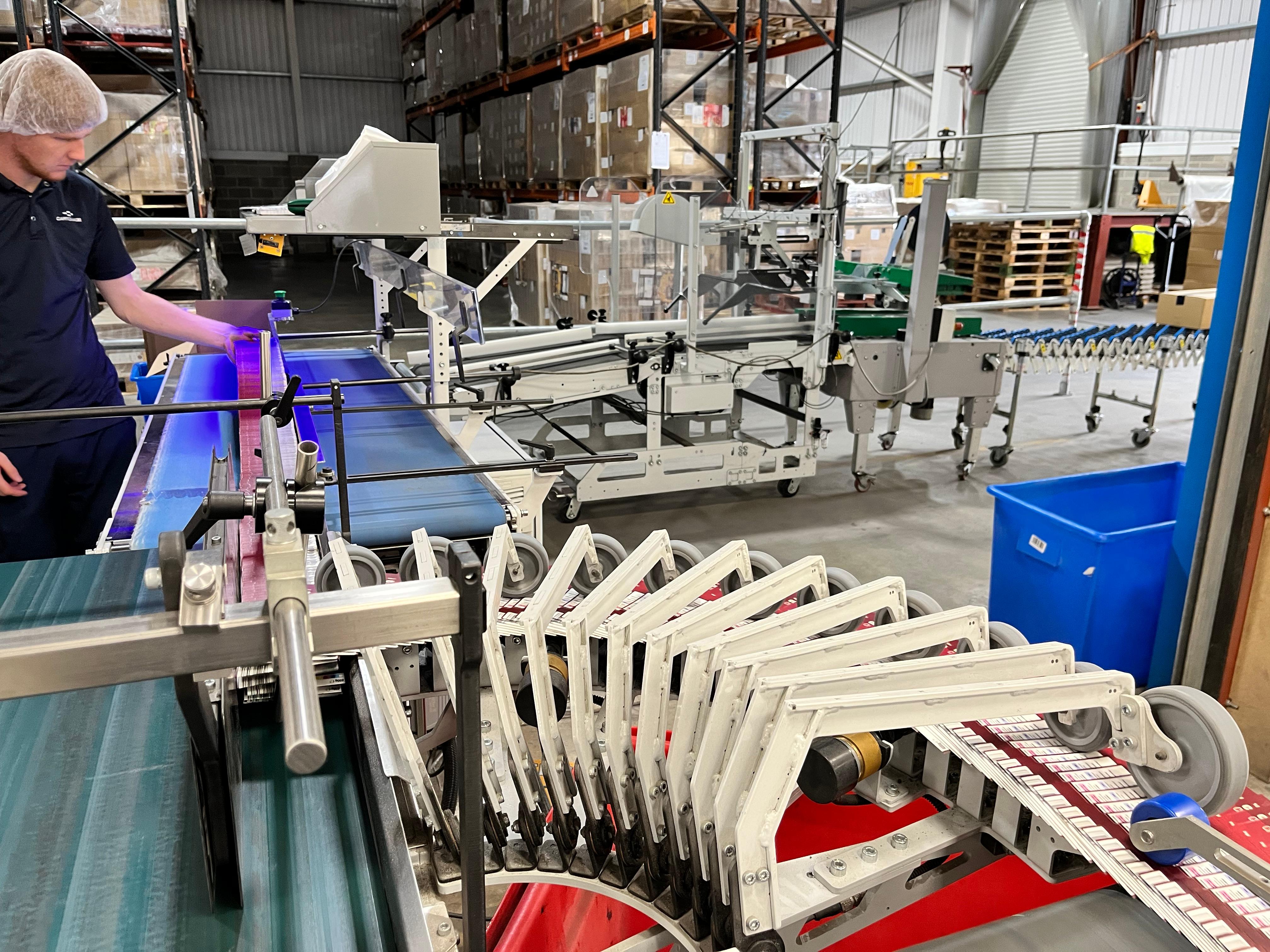 Man operates the Ergosa folded carton packing solution, box turner in the foreground