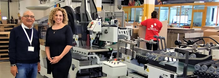 Marie-Soleil stands alongside a client, with an IMPACK ERGOSA visible in the background. 