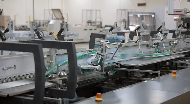 Carton blanks are being folded as they pass through the folder-gluer at high speeds