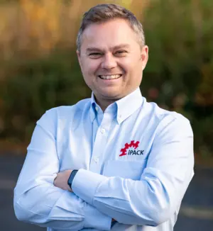 John HallJohn Hall of iPack Solutions, IMPACK’s UK agent, smiling with his arms crossed and wearing a light blue shirt with the iPack Solutions logo.
